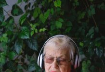 senior woman in headphones using smartphone